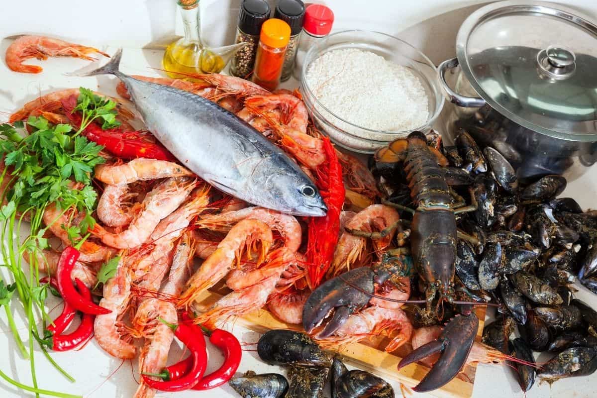 Assortment of seafood including fish, shrimp, lobster, and mussels on a table.